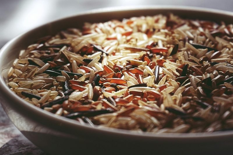 Macro shot of a ceramic bowl filled with colorful mixed wild rice, highlighting textures.