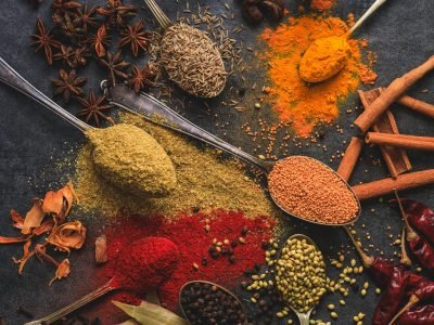 Vibrant array of spices including turmeric, cumin, and chili arranged on a dark surface.